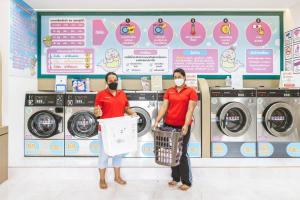 two people standing in a laundry room with a wall with signs at T-Bird Grand Hotel Trang ทีเบิร์ดแกรนด์ in Trang