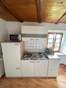 a kitchen with white cabinets and a sink and a microwave at Le Cocon du Vignoble - Free Wifi - Netflix in Turckheim