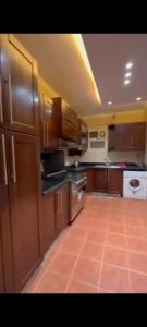a large kitchen with wooden cabinets and a tile floor at Golden in Mossadak Tower in Cairo