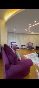 a purple couch in a room with purple chairs at Golden in Mossadak Tower in Cairo