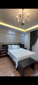 1 dormitorio con 1 cama blanca grande con lámpara de araña en Golden in Mossadak Tower en El Cairo