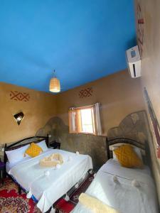 two beds in a bedroom with a blue ceiling at Auberge Agoudal in Agoudal