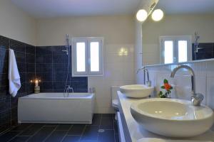 a bathroom with two sinks and a bath tub and a tubermott at Villa Gaia in Dassia