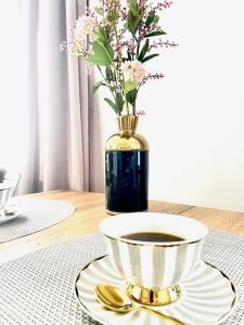 una mesa con una taza de café y un jarrón con flores en DOMAX en Legnica