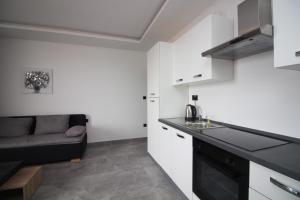 a kitchen with white cabinets and a couch in a room at Apartments Toni in Primošten