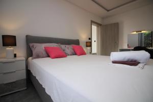 a bedroom with a large white bed with red pillows at Apartments Toni in Primošten