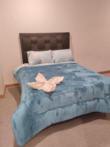 Una cama con un edredón azul con una flor. en Hermoso departamento en La Paz-Bolivia, en La Paz
