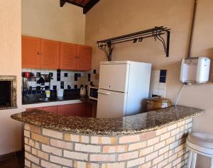 a kitchen with a brick counter with a refrigerator at Hostel Oktoberfest casa laranja in Blumenau