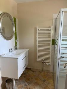 La salle de bains est pourvue d'un lavabo blanc et d'un miroir. dans l'établissement Maison de charme en pleine nature, à Saint-Germain-des-Grois