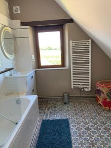 La salle de bains est pourvue d'une baignoire, d'un lavabo et d'une fenêtre. dans l'établissement Maison de charme en pleine nature, à Saint-Germain-des-Grois