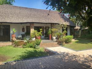 uma casa com telhado de palha e um pátio em Harties Lodge - Rose Cottage em Hartbeespoort