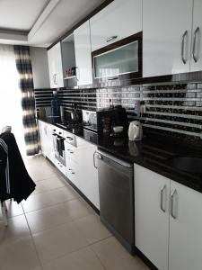 eine Küche mit weißen Schränken und schwarzen Arbeitsplatten in der Unterkunft Wohnung in Mahmutlar