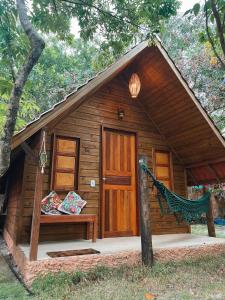 a small wooden cabin with a bench in front of it at Eco Glamping Caraiva in Caraíva