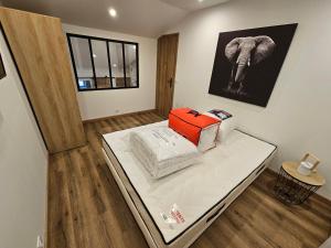 una camera con un letto con una valigia arancione sopra di Maison entière proche plage a Saint-Léonard