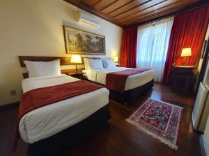 a hotel room with two beds with red curtains at Hotel Pousada do Arcanjo in Ouro Preto