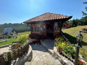 une petite maison avec un jardin fleuri en face dans l'établissement Vila Zorica Vodice, à Zlatibor