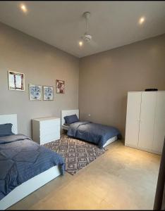 1 Schlafzimmer mit 2 Betten und einem Teppich in der Unterkunft استراحة النيروز in Ras al-Hadd