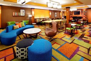 a hotel lobby with blue couches and tables and chairs at Fairfield Inn & Suites Pittsburgh Neville Island in Robinson Township