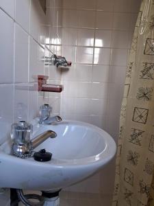 a white sink in a bathroom with a shower curtain at KASP Cottage in Underberg