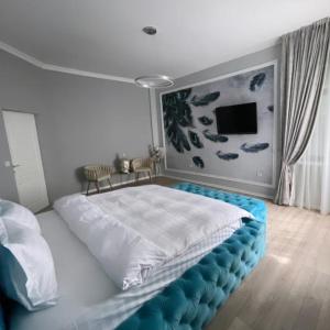 a bedroom with a large white bed with blue padding at Casa Di David in Buzău +3 photos