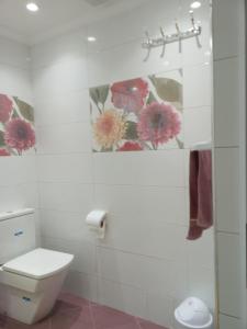 a bathroom with a toilet and a flower painting on the wall at شقة جميلة وهادئة in Agadir