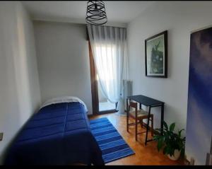 a bedroom with a blue bed and a table at Verdisuite - Trento centro - Parcheggio privato gratuito in Trento