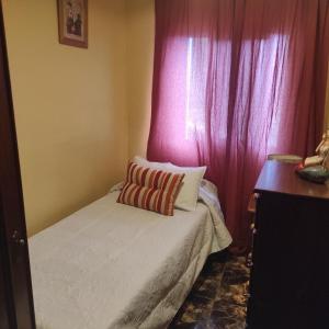 a small bedroom with a bed with a pink curtain at CASA ROSAMAR in Agulo