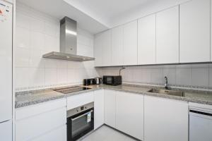 a white kitchen with white cabinets and appliances at Villa Montelimar - Biznaga Rental Homes in Rincón de la Victoria