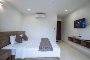 1 dormitorio con 1 cama y TV en la pared en AURORA BÃI CHÁY HẠ LONG en Ha Long
