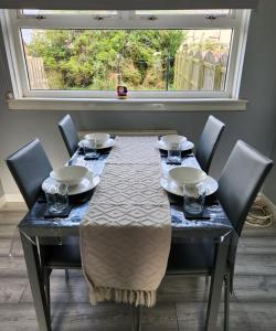 a dining room table with chairs and a large window at Stunning 3 bedroom FMHomes & Apartments in Uddingston