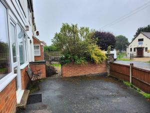 una casa con una pared de ladrillo y una valla en * Cotswolds Get-Away Annex *, en Cleeve Prior