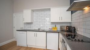 eine weiße Küche mit weißen Schränken und einem Waschbecken in der Unterkunft 2 BDR apartment at QUEENS UNI by Belfast City Breaks in Belfast