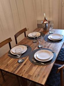 Una mesa de madera con platos y copas de vino encima. en Self Contained City Apartment, en Perpiñán 12 fotos más