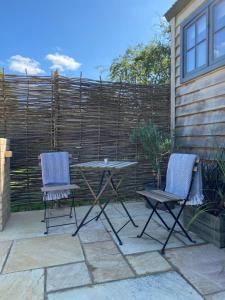 two chairs and a table in front of a fence at The Rabbit Warren Shepherd Hut in Ketton