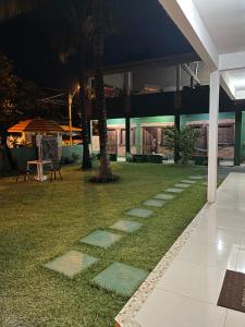 a grassy yard with a walkway in front of a building at Pousada Luz da Vila Itaúnas in Itaúnas