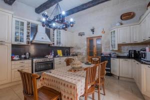 una cocina con mesa y sillas y una cocina con armarios blancos. en Vintage farmhouse en Qormi