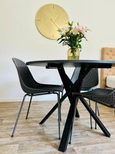 a black dining room table with two chairs and a clock at Apartman Mikulov Garden in Mikulov