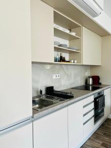 a white kitchen with white cabinets and a sink at Apartman Mikulov Garden in Mikulov