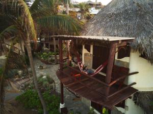 a person sitting in a hammock in a house at Cabañas Punta Placer in San Agustinillo
