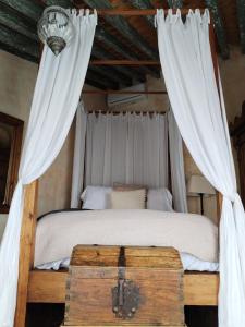 a bedroom with a canopy bed with a wooden trunk at Hacienda Las Amantes in San Miguel de Allende