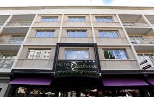 un grand bâtiment avec un panneau devant lui dans l'établissement Hôtel Des Quatrans, à Caen