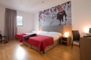 a hotel room with two beds and a painting on the wall at IRAIPE Pamplona Hostal in Pamplona