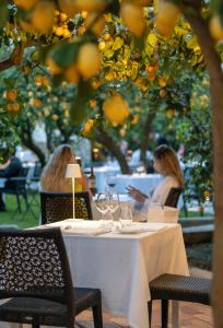 two women sitting at a table under an orange tree at Boutique Hotel Casa Mariantonia in Anacapri