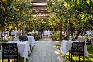 阿納卡普里的住宿－卡薩瑪麗安冬妮婭精品酒店，一间拥有白色桌椅和橘子树的餐厅