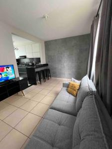 a living room with a gray couch and a kitchen at Apartamento na Zonal Sul 2 Vagas Carro in Uberlândia