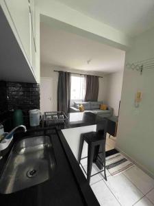 a kitchen with a sink and a living room at Apartamento na Zonal Sul 2 Vagas Carro in Uberlândia