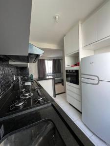 a kitchen with a stove and a white refrigerator at Apartamento na Zonal Sul 2 Vagas Carro in Uberlândia