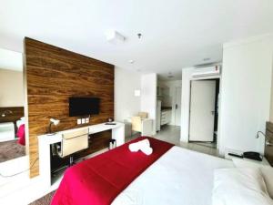 a bedroom with a large bed with a desk and a monitor at Lindo flat no Vision - centro de Brasília in Brasilia