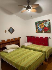 Villa G55C RosaMarina في روزا مارينا: غرفة نوم بسريرين ومروحة سقف