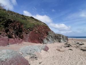 a sandy beach with some rocks and a cliff at Le Chalet - 2 Bedroom Chalet House sleeps 3 in Pembrokeshire